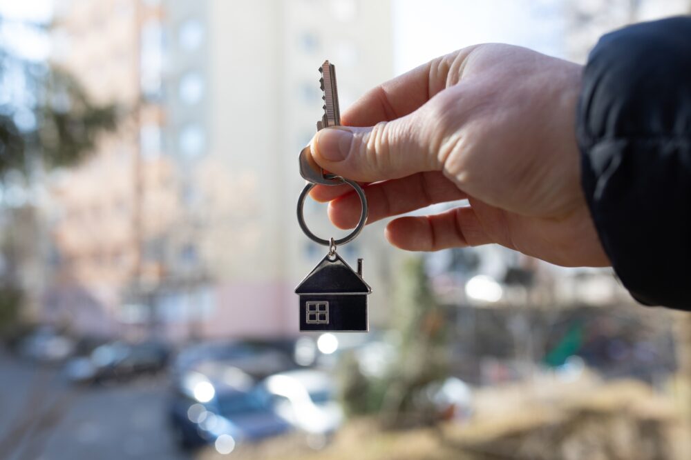 Hand holding key, buildings in the background