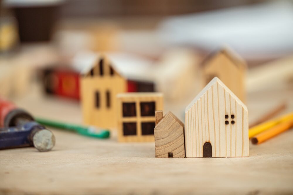 small big wooden house on builder table with tools for build new home scale size compare concept.